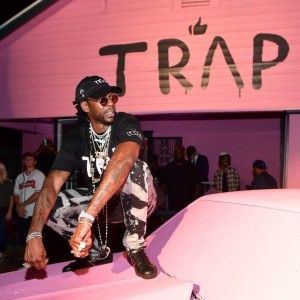 a man sitting on the hood of a white car in front of a pink building