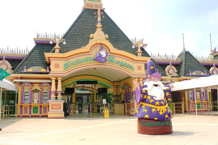 the entrance to an amusement park with a large purple and yellow statue in front of it