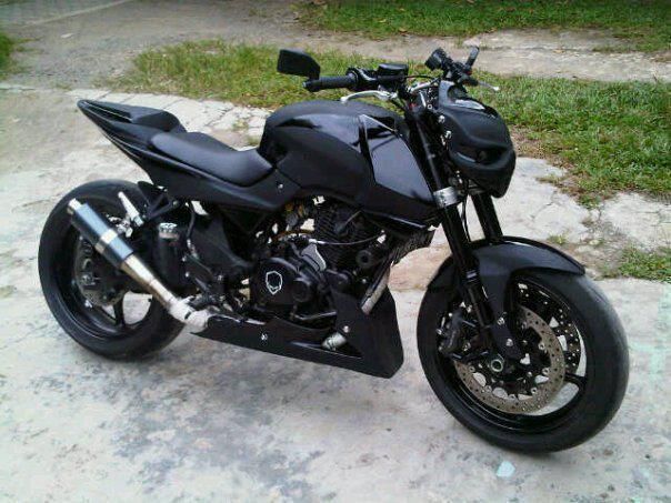 a black motorcycle parked on top of a sidewalk