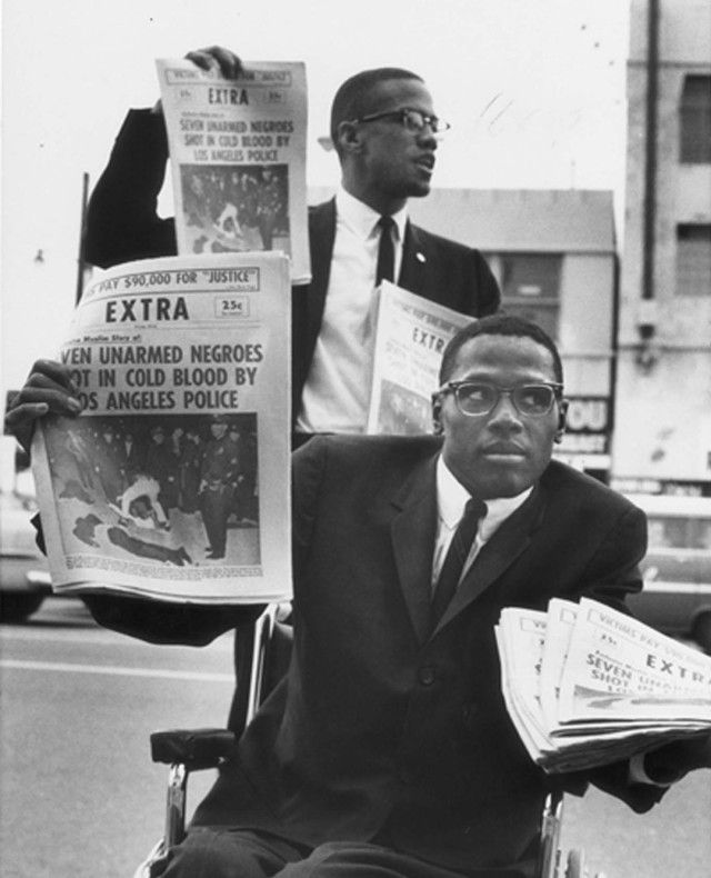 a man sitting in a wheel chair holding newspapers