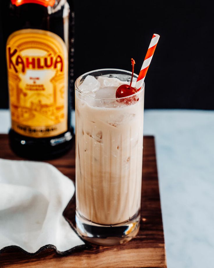 a drink sitting on top of a wooden table next to a bottle