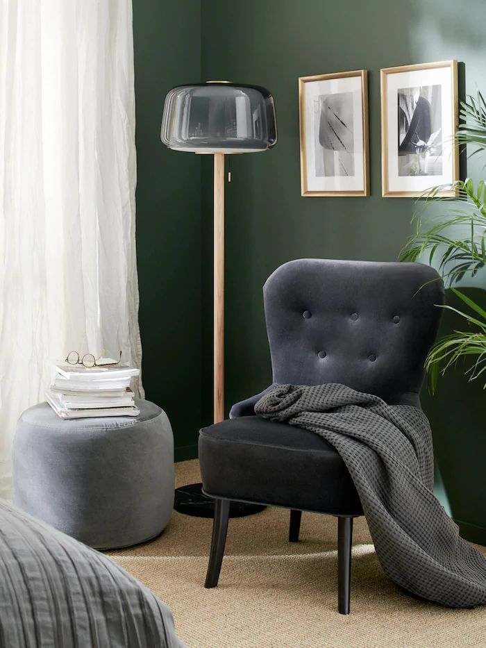 a chair with a blanket on it next to a lamp and pictures hanging on the wall