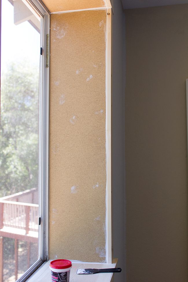 a window sill with paint on it next to a cup and brush in front of the window