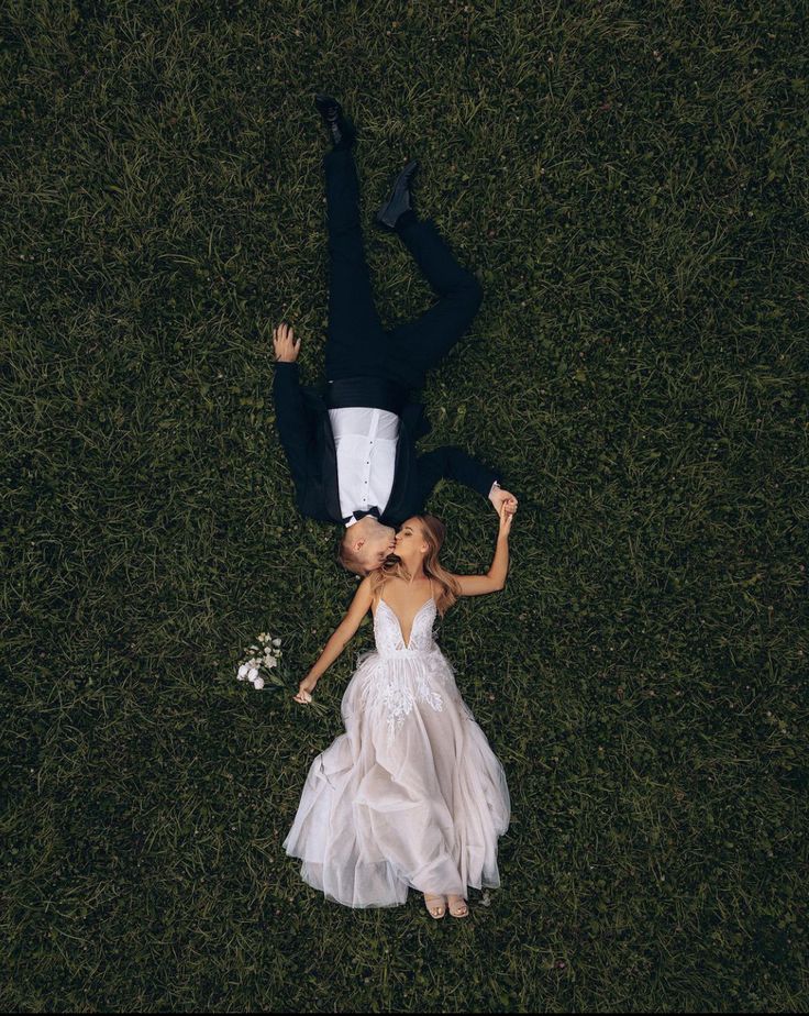 a bride and groom laying in the grass