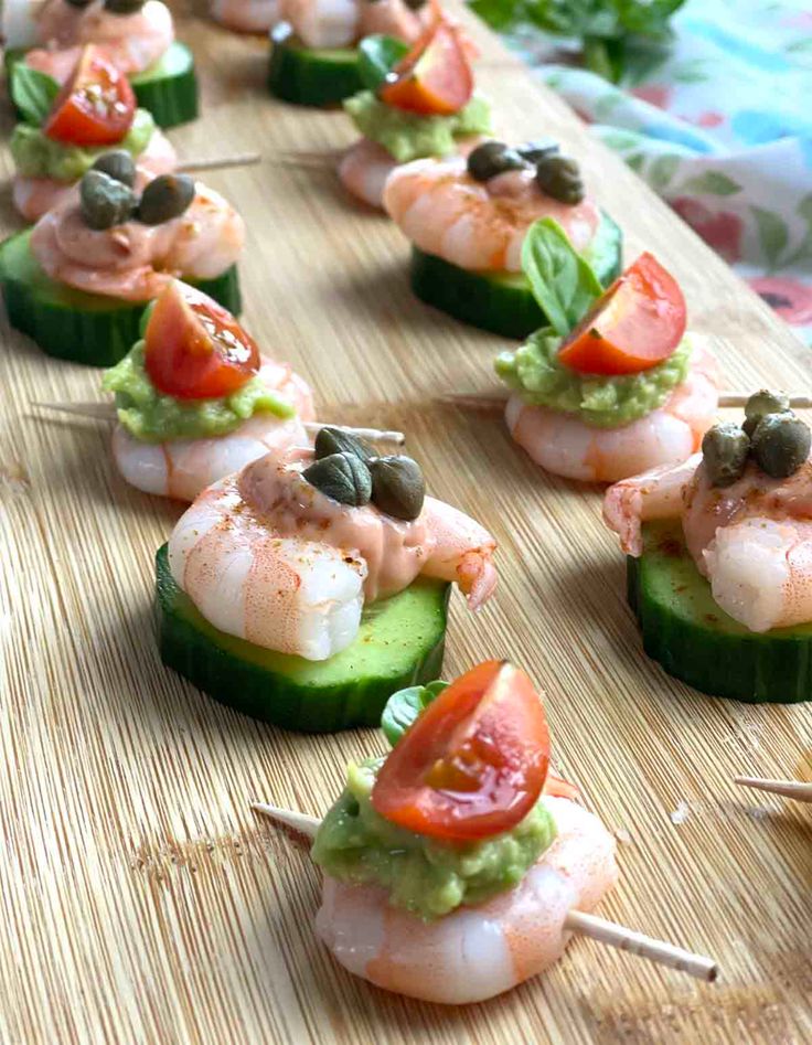 cucumber and shrimp appetizers are arranged on a wooden board