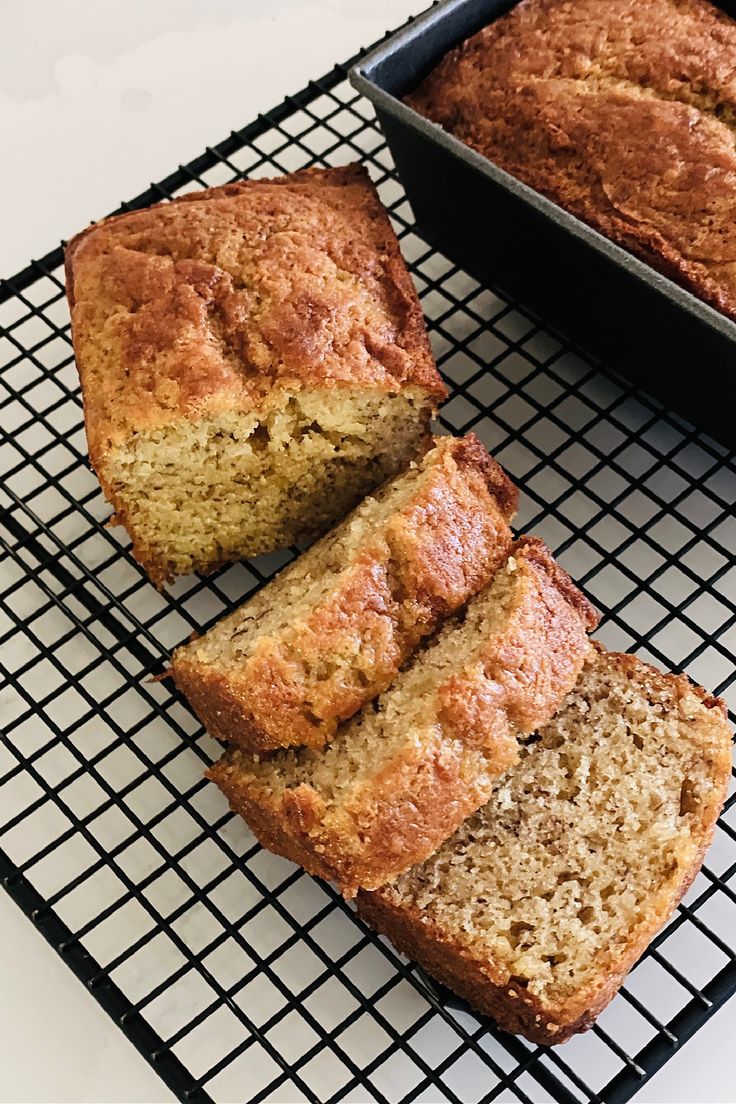 slices of banana bread sitting on a cooling rack next to a loaf of cake in a pan