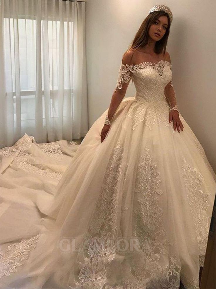 a woman in a white wedding dress standing on a bed with her hands on her hips