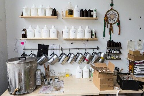 the shelves are full of bottles and containers on the wall behind the coffee maker's workbench