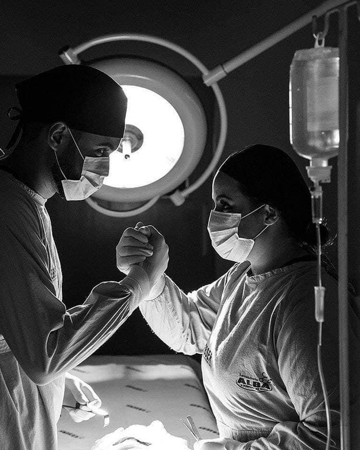 a man and woman in scrubs standing next to each other with their hands together