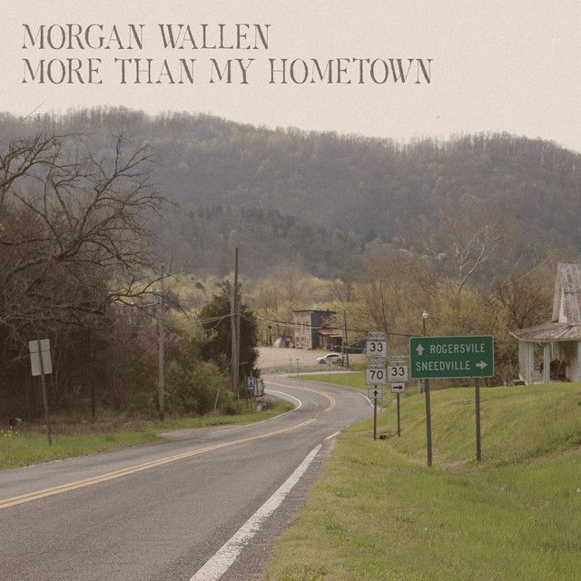 an empty road with a sign on the side and mountains in the background that says morgan allen more than my home town