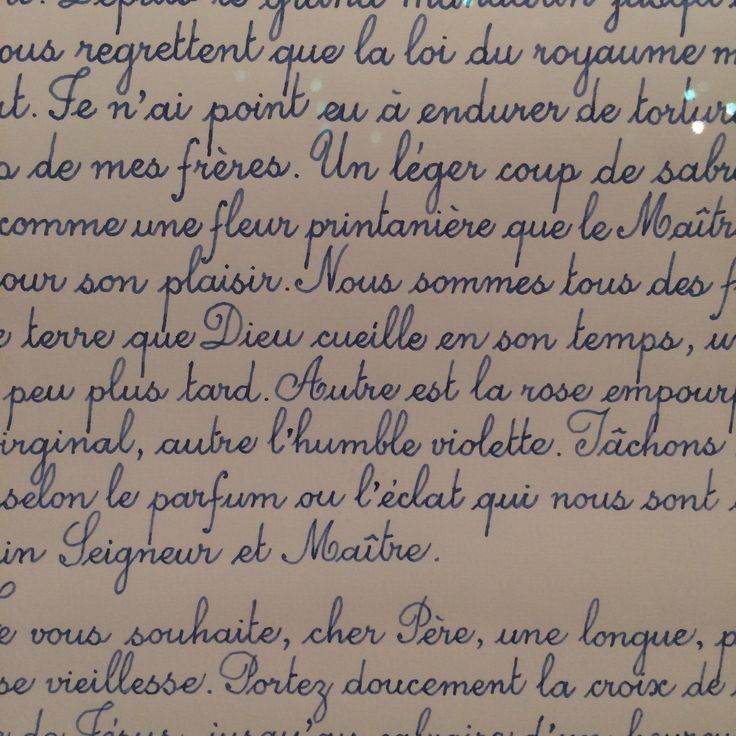 handwriting written in french on white paper with blue ink and writing underneath the letters are cursive