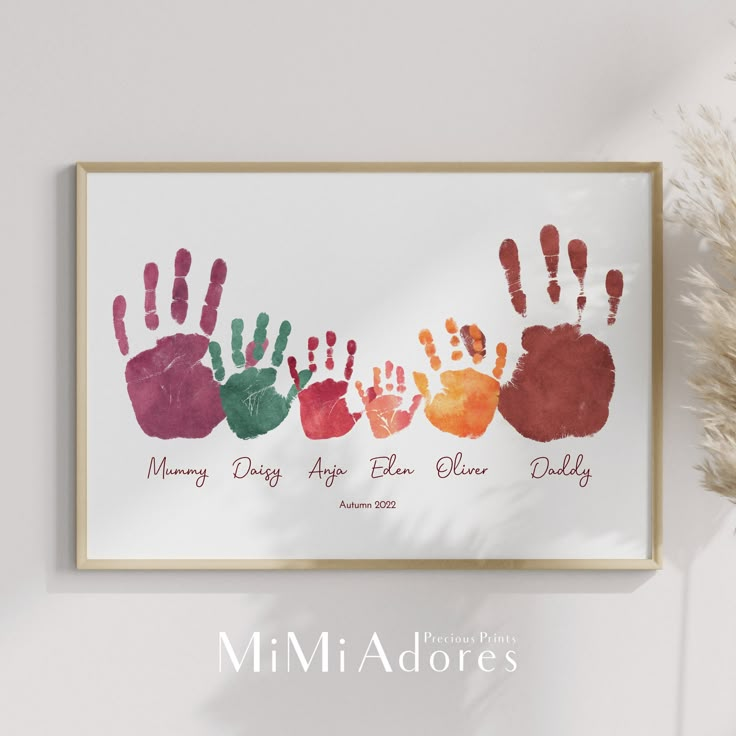 a family handprint is displayed on the wall next to a vase with dried flowers