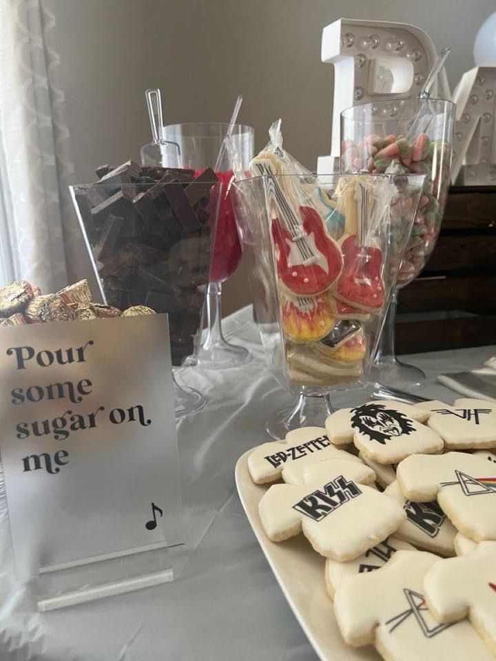 some cookies are sitting on a table next to a glass vase with candy in it