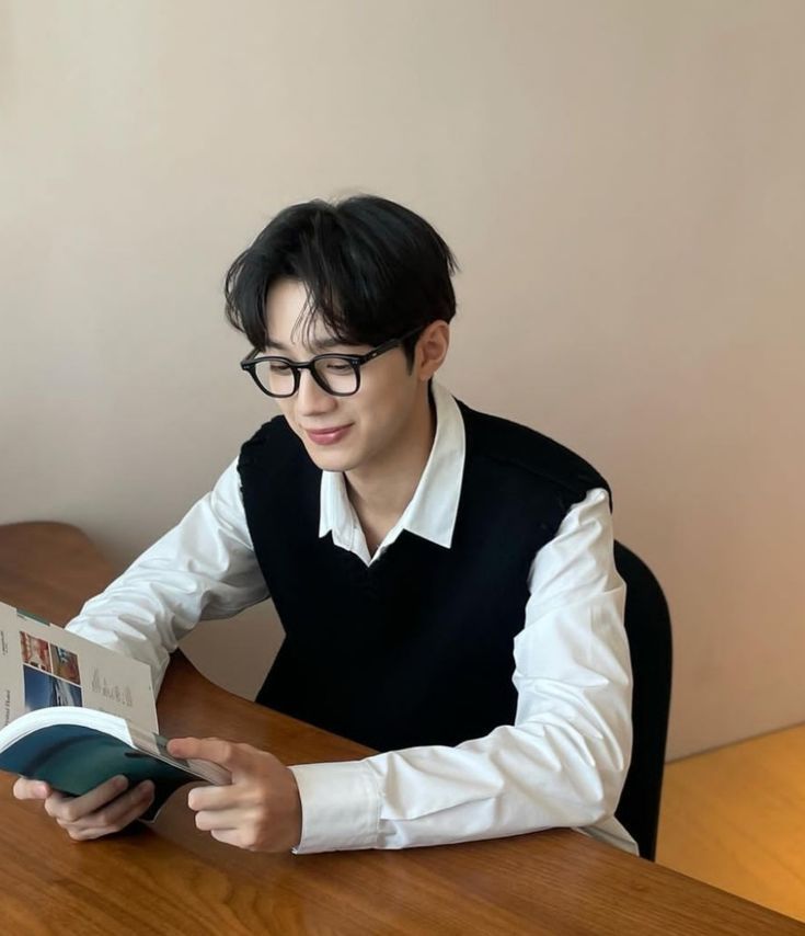 a man sitting at a desk reading a book