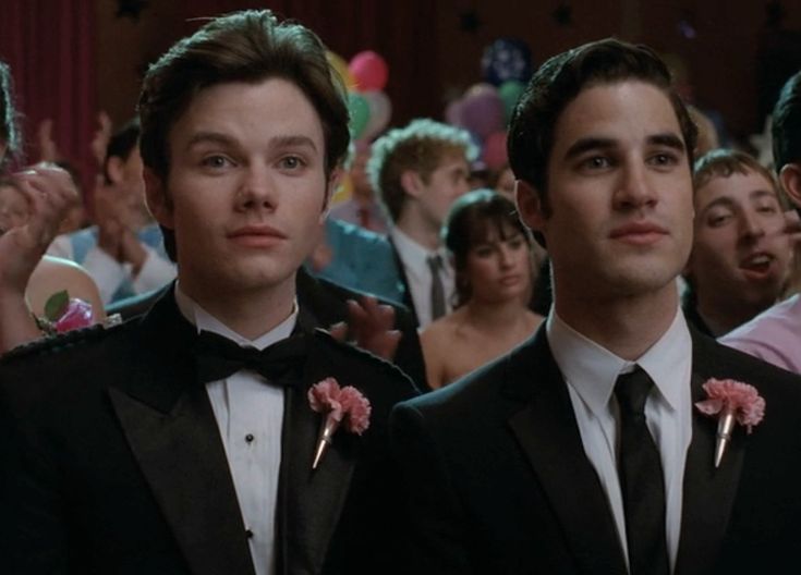 two young men in tuxedos standing next to each other at a formal event