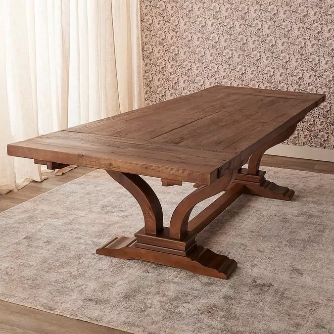 a wooden table sitting on top of a rug in front of a curtained window