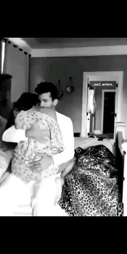 black and white photograph of two people hugging each other in a room with leopard print bedding