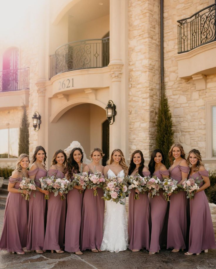 a group of women standing next to each other in front of a building with flowers