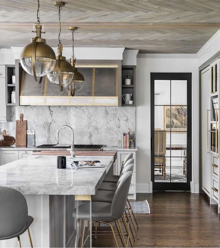 a kitchen with marble counter tops and gold pendant lights hanging from the ceiling over the island