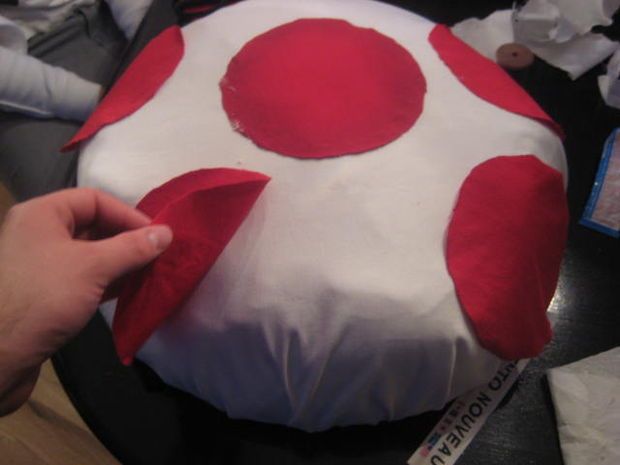 someone is decorating a cake with red and white polka dots on it's top