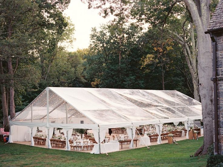 a large tent set up in the middle of a grassy area with tables and chairs