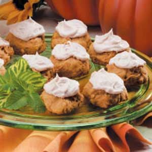 a glass plate topped with cookies covered in frosting next to flowers and pumpkins