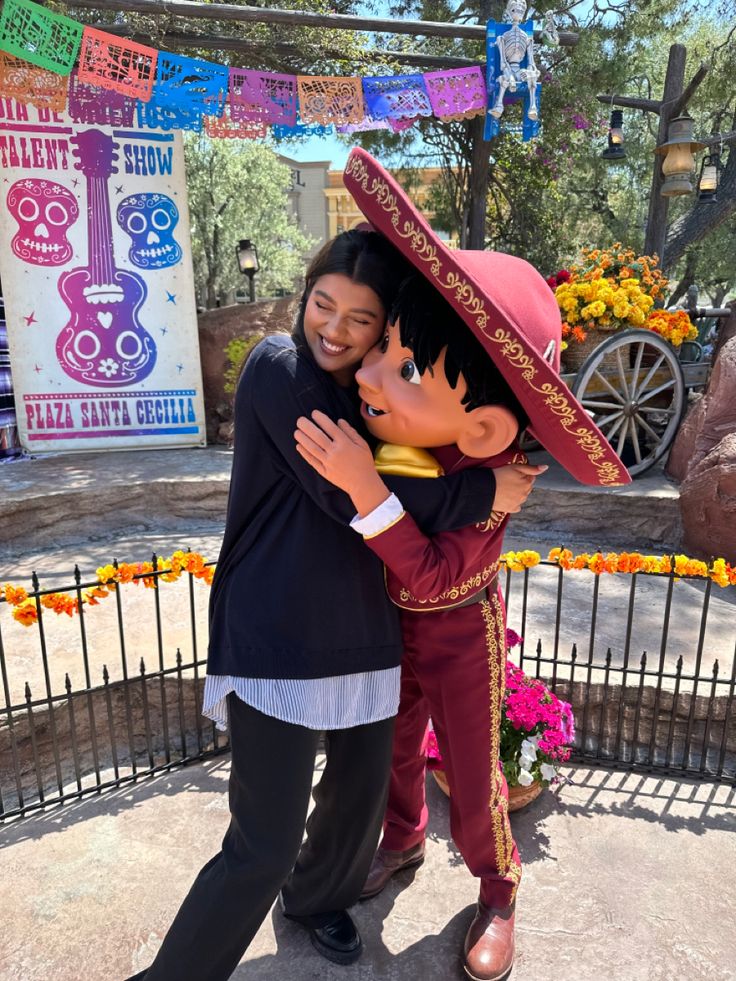 two people hugging each other in front of a sign with flowers and decorations on it