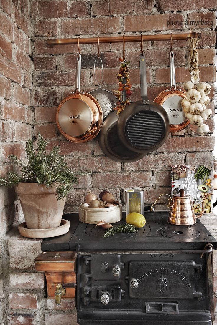 an old stove with pots and pans hanging on the wall