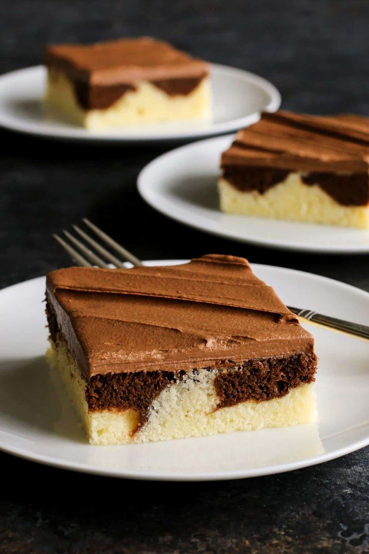 two white plates with slices of cake on them and one slice has chocolate frosting