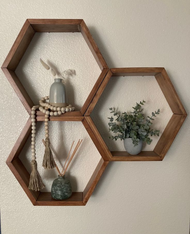 three wooden hexagonal shelves with plants and beads on them hanging from the wall