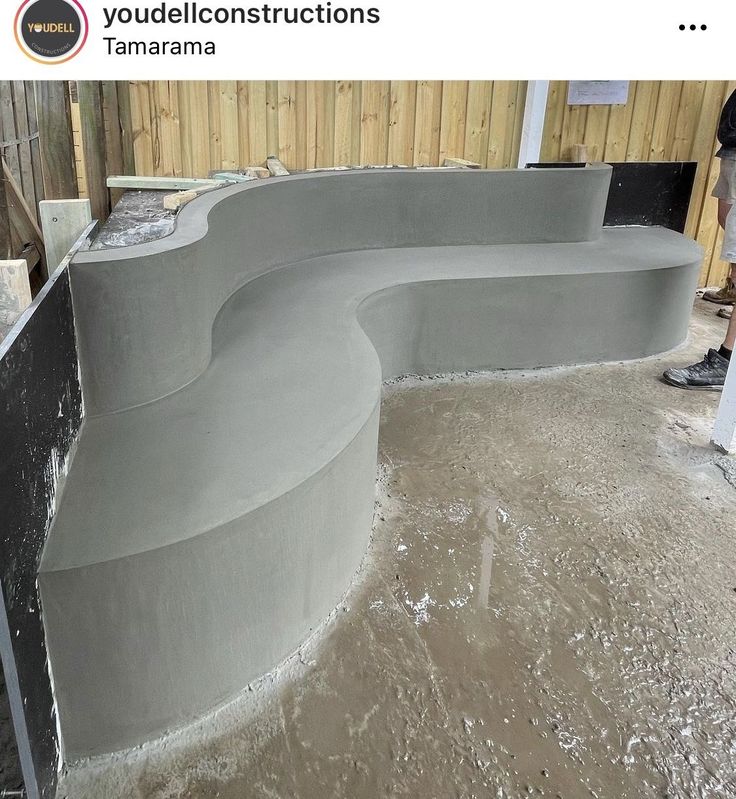 a man standing next to a concrete bench in the process of being poured with cement