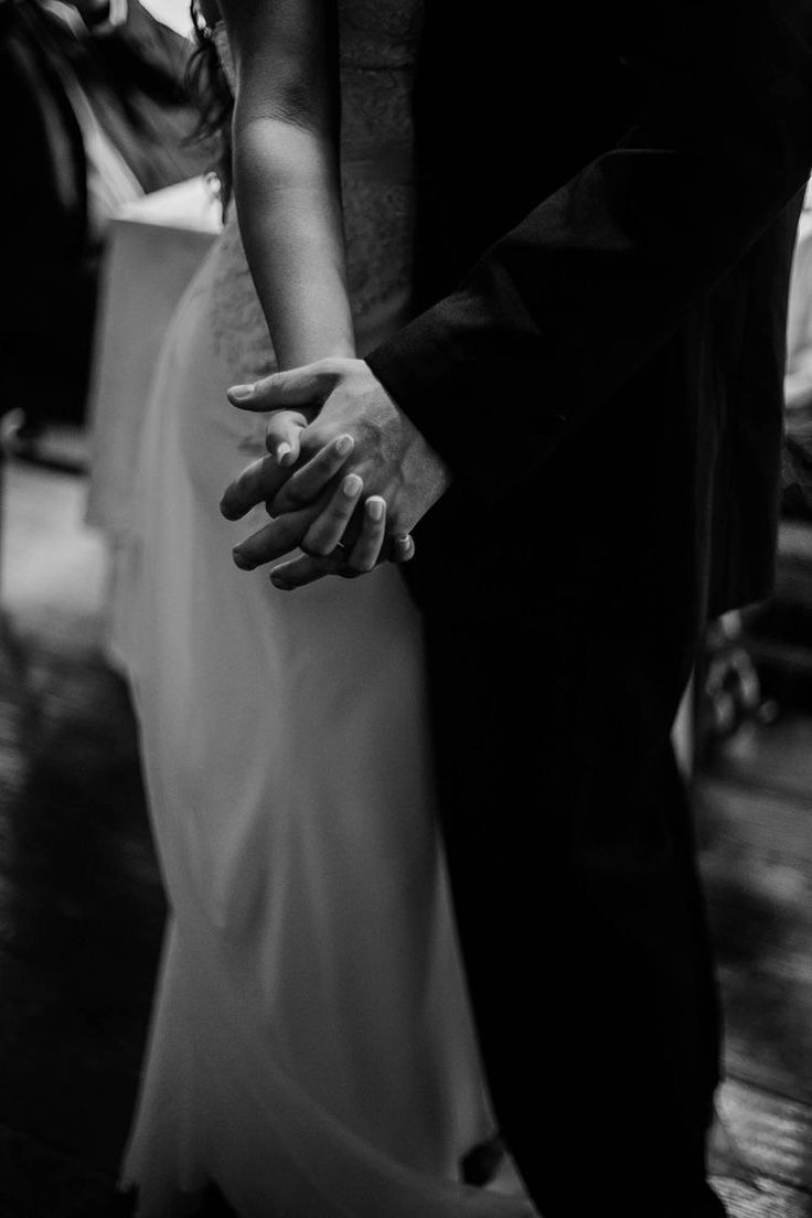 black and white photograph of a bride and groom holding each other's hands as they dance