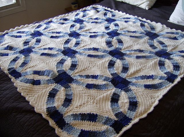 a crocheted blanket on top of a bed in a room with a window