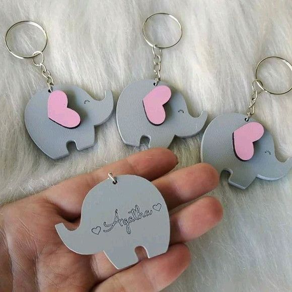 three elephant keychains with pink hearts on them are being held by someone's hand