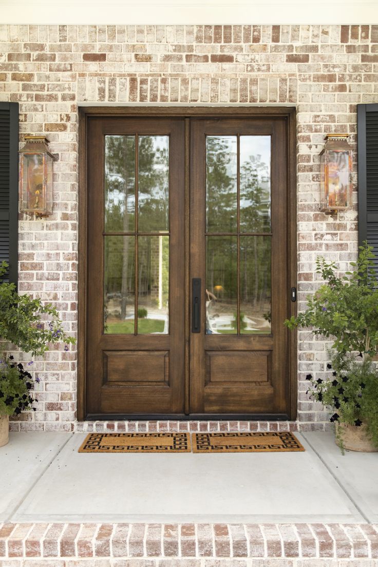 the front door to a home with two potted plants on either side and an entry mat