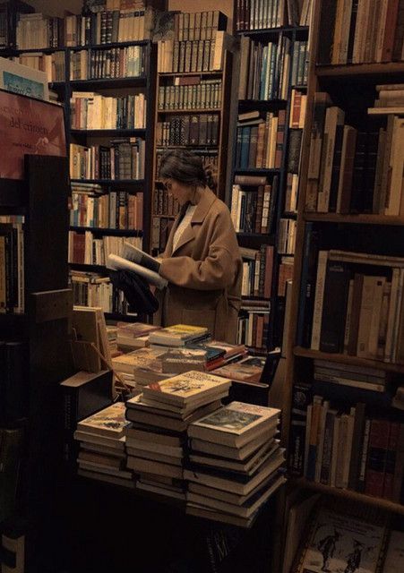 a woman standing in front of a book shelf filled with books