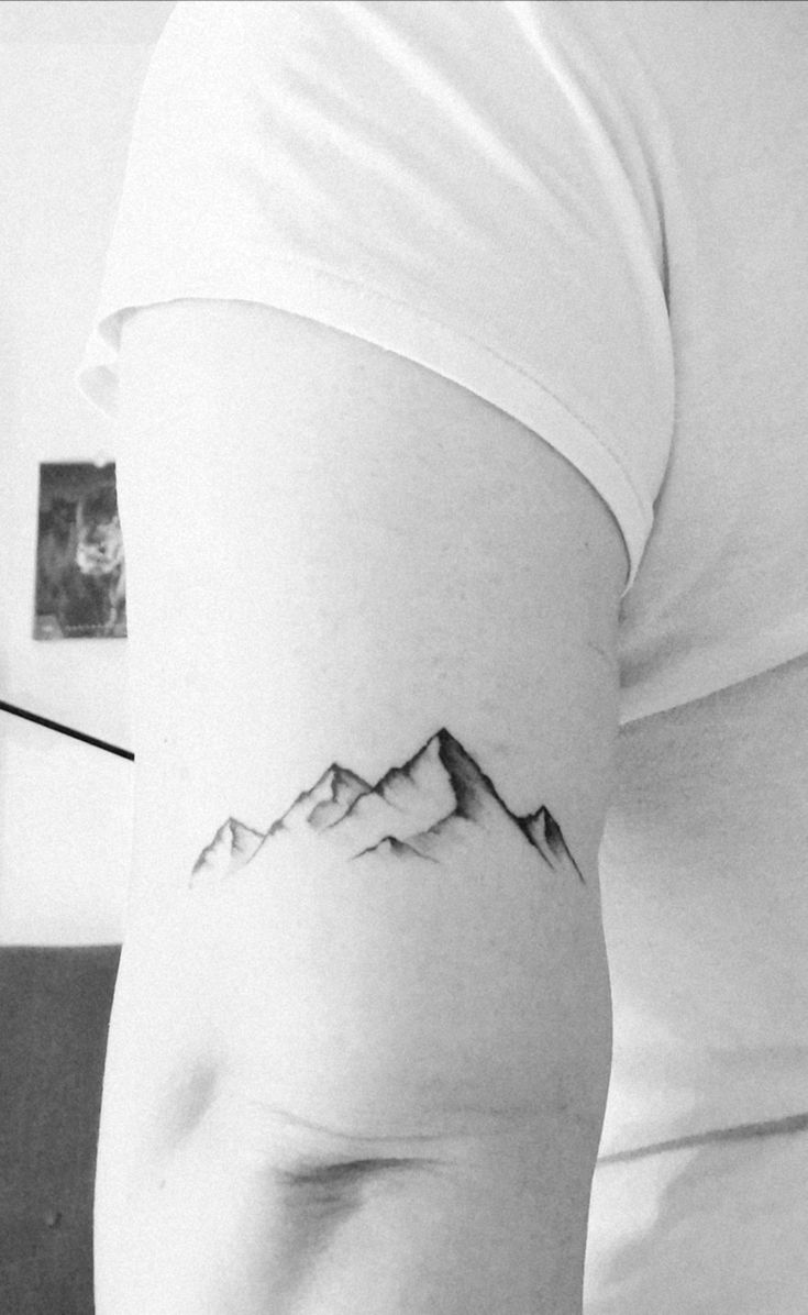 a black and white photo of a mountain tattoo on the back of a woman's left arm