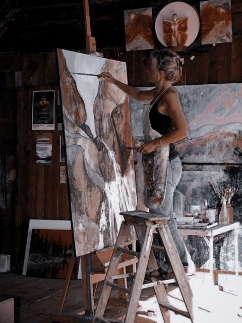 a woman is painting on an easel in her studio