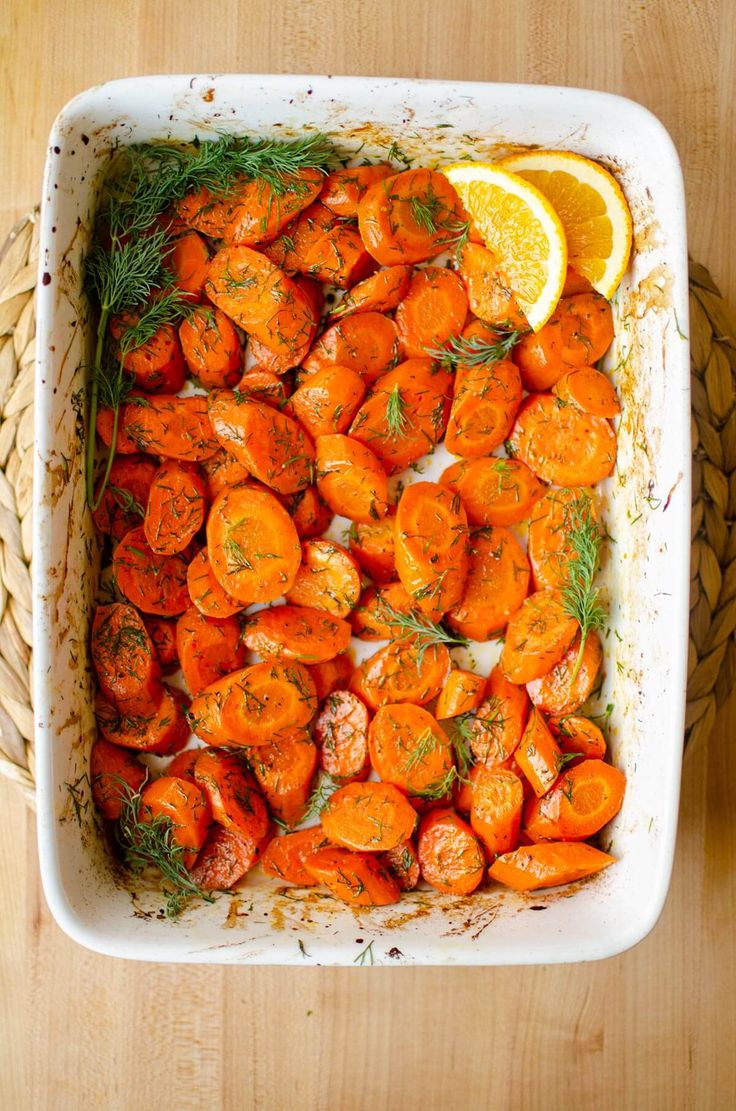 a casserole dish with carrots, lemon and herbs