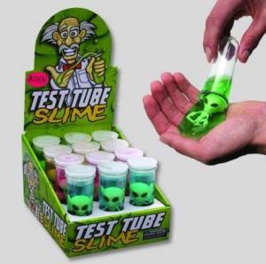 a hand holding a tube filled with green liquid next to a box of test tubes