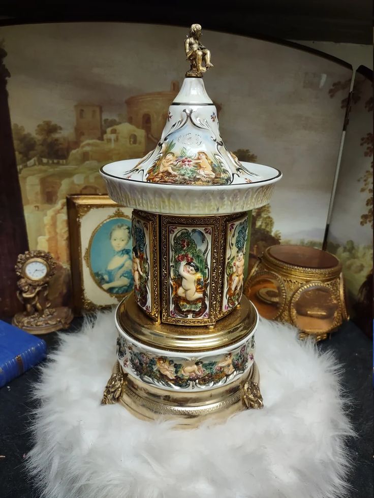 an ornately decorated urn on display in front of a wall with other items