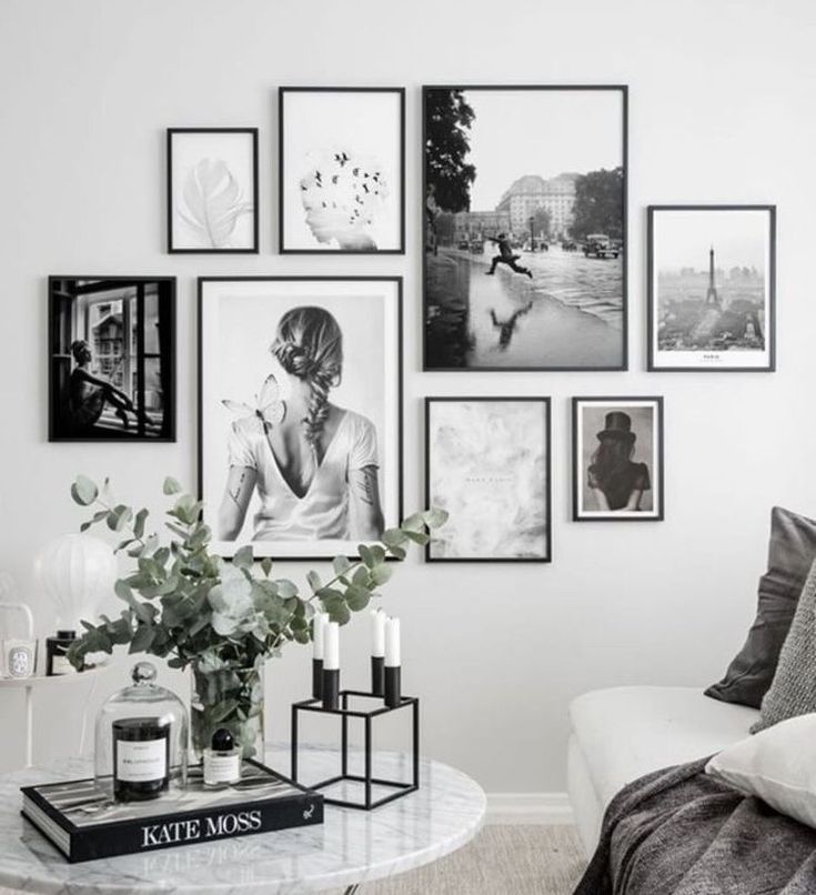 black and white photographs hang on the wall above a couch in a living room with a coffee table