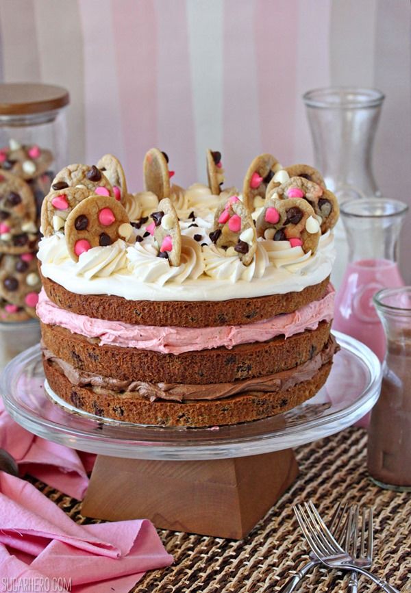 a cake with white frosting and pink icing is on a glass platter