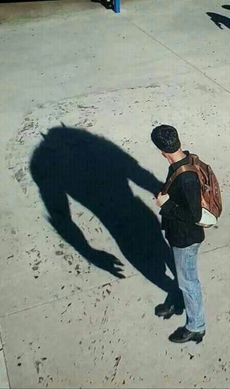 a man standing in front of a sidewalk with his shadow on the ground and someone's back