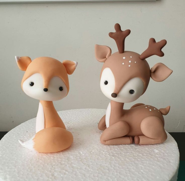 two little deer figurines sitting on top of a cake