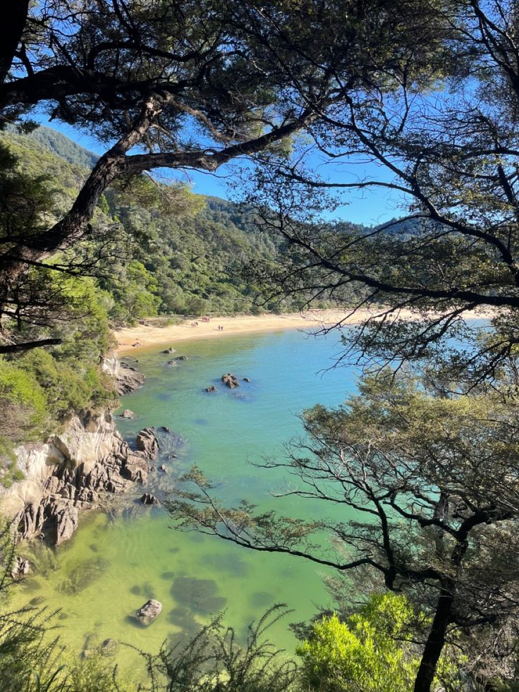 a lake surrounded by trees and rocks in the middle of a wooded area with clear blue water