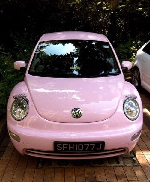 a pink vw beetle parked in front of a white car with eyelashes on it