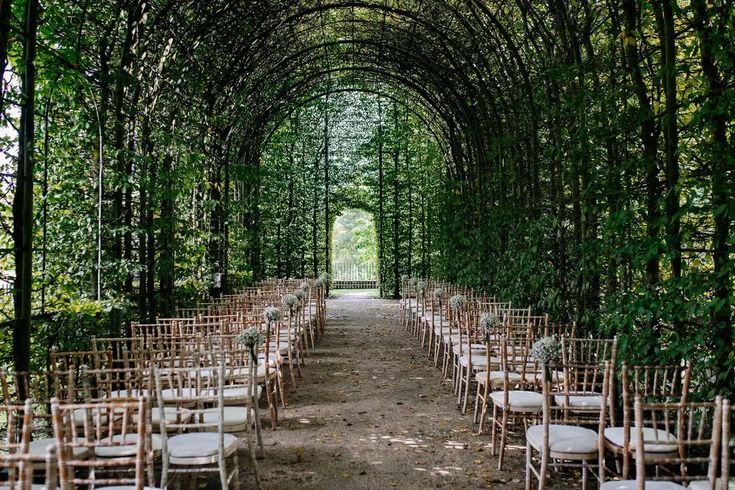 an outdoor wedding venue set up with white chairs and greenery