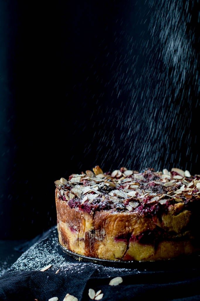 a cake is being sprinkled with icing and powdered sugar on a black surface