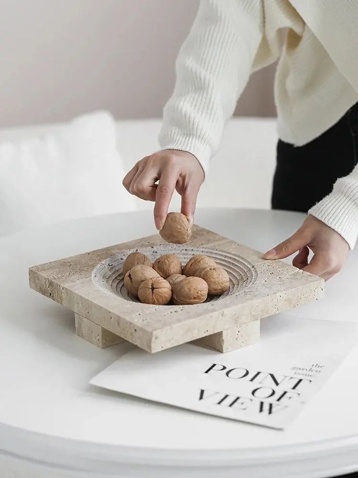 a person placing rocks in a bowl on a table